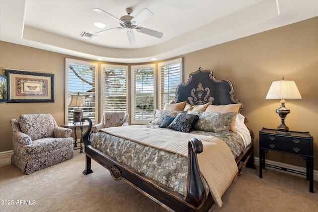 bedroom featuring a tray ceiling, visible vents, ceiling fan, and light carpet