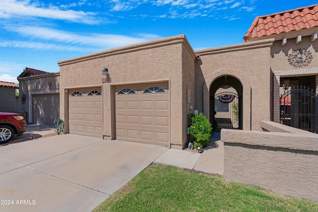 view of front of home with concrete driveway, stucco siding, a tiled roof, and an attached garage