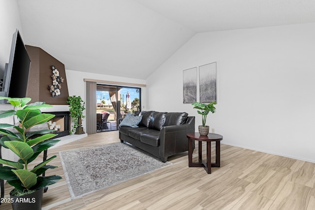 living area with light wood-style floors, baseboards, and vaulted ceiling