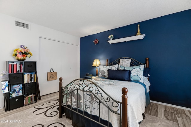 bedroom featuring a closet, visible vents, baseboards, and wood finished floors