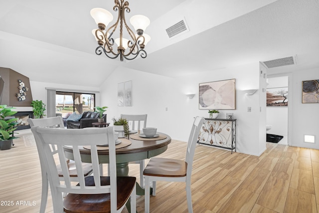 dining area with visible vents, light wood-style flooring, a notable chandelier, and lofted ceiling