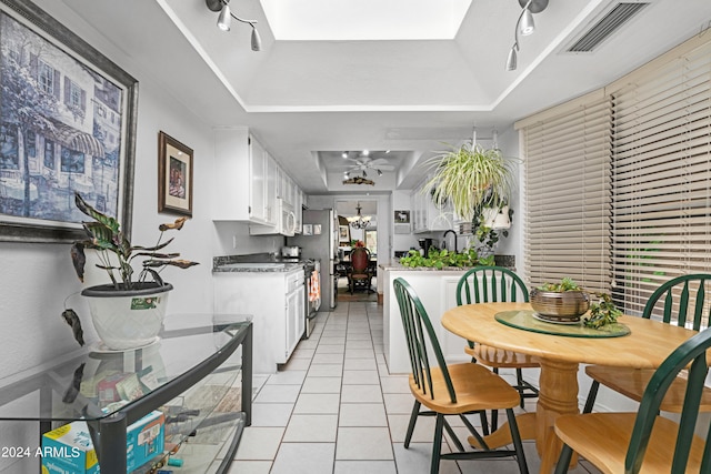 dining area featuring light tile patterned floors, visible vents, a raised ceiling, and a ceiling fan