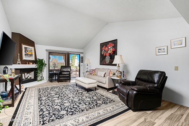 living room featuring a textured ceiling, wood finished floors, a fireplace, and vaulted ceiling