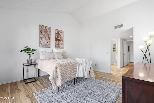 bedroom with visible vents, light wood-style flooring, baseboards, and lofted ceiling