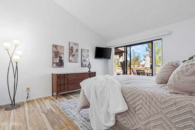bedroom with lofted ceiling, access to exterior, baseboards, and wood finished floors
