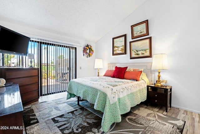 bedroom featuring baseboards, vaulted ceiling, wood finished floors, a textured ceiling, and access to outside