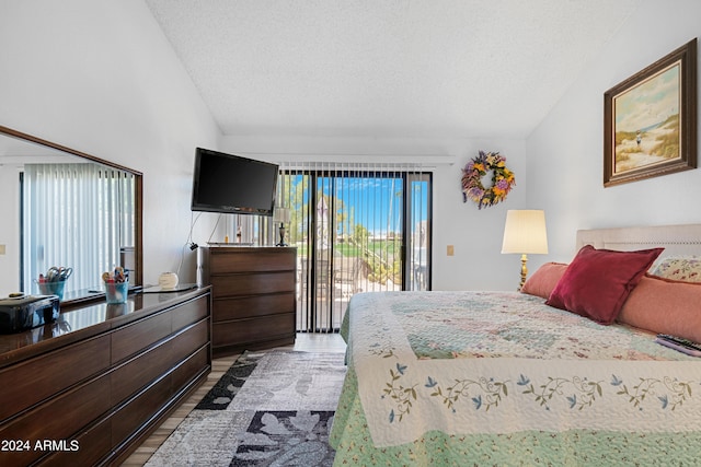 bedroom featuring lofted ceiling, access to outside, light wood finished floors, and a textured ceiling