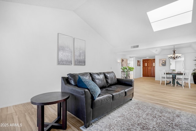 living room featuring an inviting chandelier, vaulted ceiling with skylight, wood finished floors, and visible vents