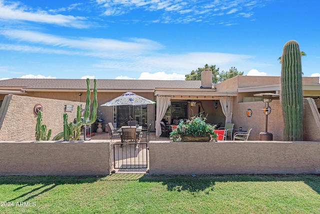 rear view of house with a yard, a patio area, fence, and a gate