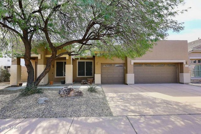 pueblo-style home with a garage, concrete driveway, and stucco siding