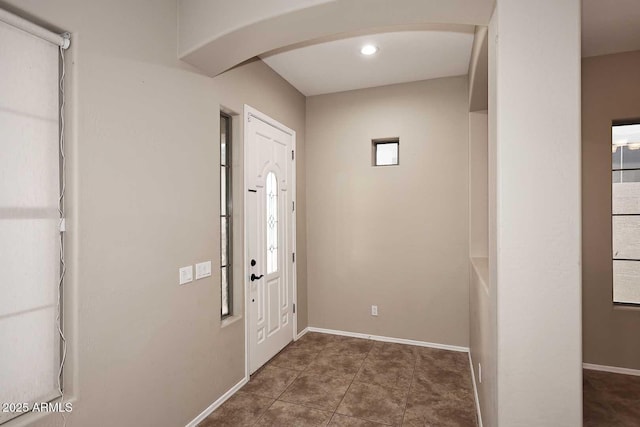 tiled foyer entrance with arched walkways and baseboards