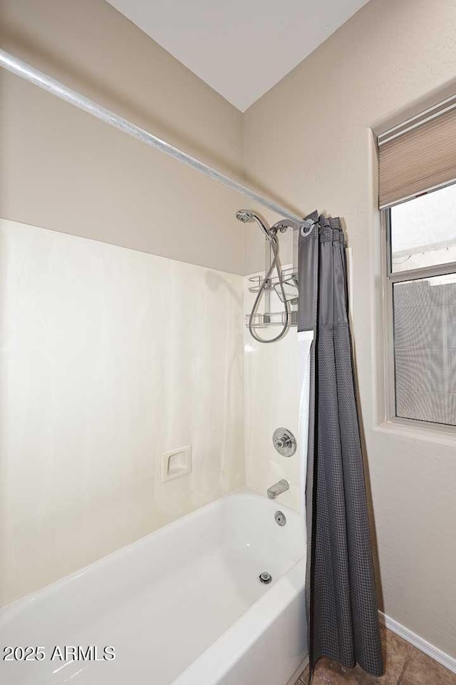 bathroom featuring baseboards and shower / bath combo with shower curtain