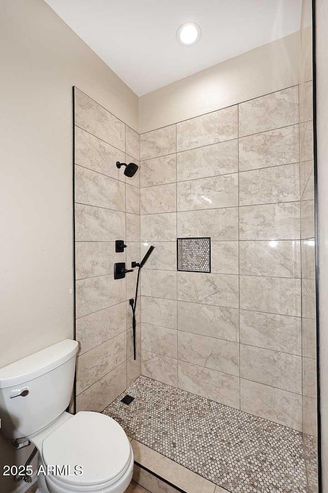 bathroom with tiled shower and toilet