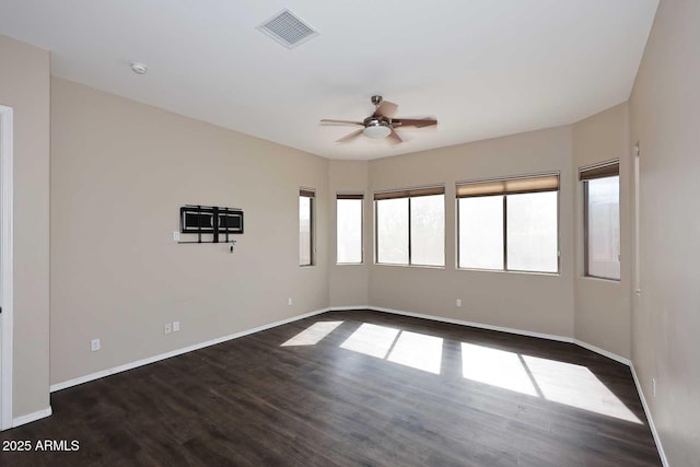 empty room with ceiling fan, dark wood-style flooring, visible vents, and baseboards