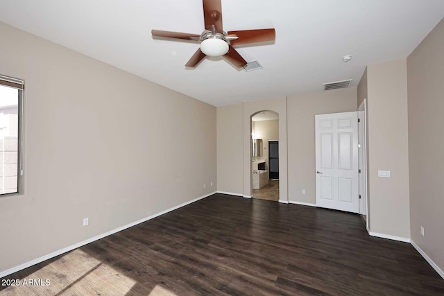 unfurnished room with arched walkways, wood finished floors, and visible vents