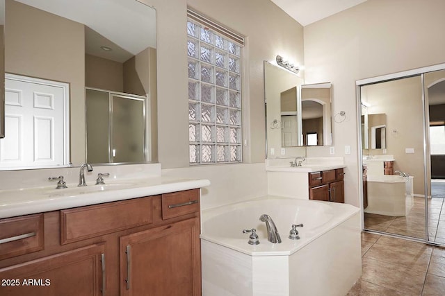 bathroom with tile patterned floors, two vanities, a stall shower, a sink, and a bath