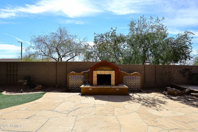 view of patio featuring a fireplace and fence