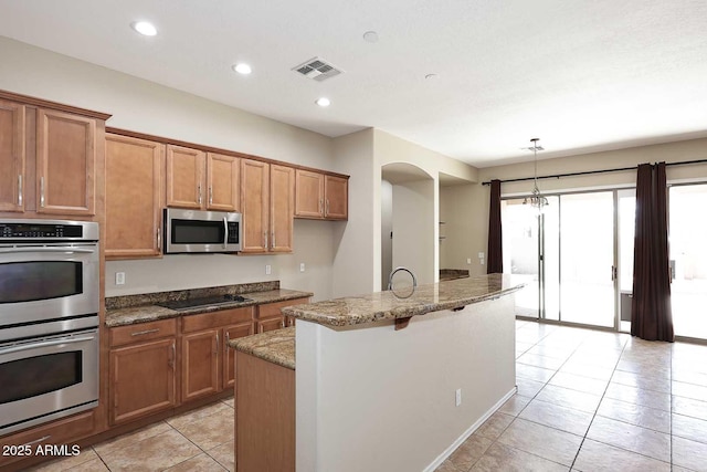 kitchen featuring brown cabinets, stainless steel appliances, recessed lighting, visible vents, and light stone countertops