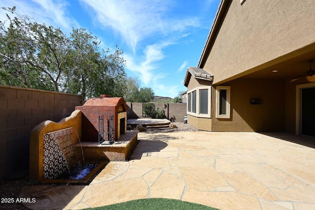 view of patio / terrace featuring a fireplace and a fenced backyard