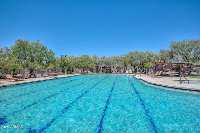 community pool with a patio area and fence