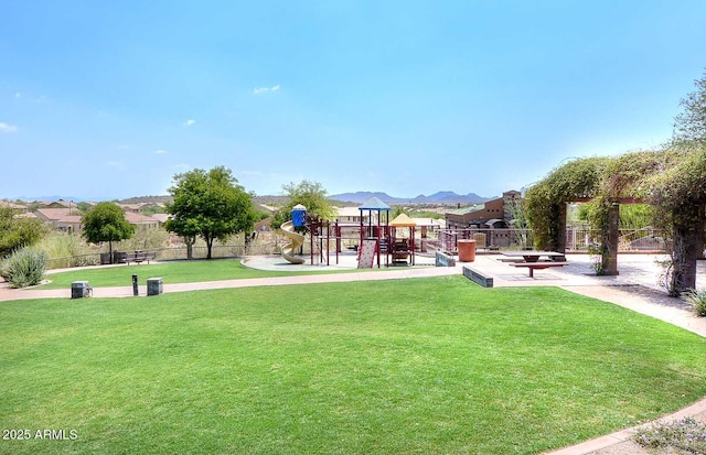 view of community with playground community, a lawn, and fence