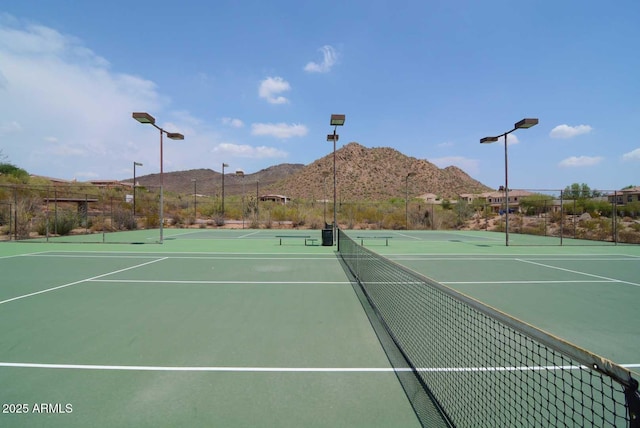 view of tennis court featuring community basketball court, a mountain view, and fence