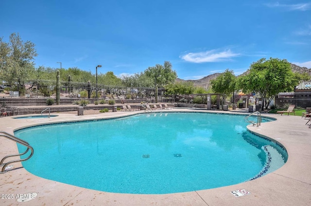 community pool with a patio area, fence, and a mountain view