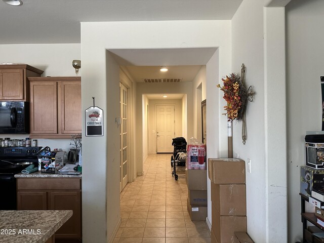 25931 W Deer Valley Rd, Buckeye, AZ 85396 - kitchen with black appliances, light tile patterned flooring, brown cabinetry, and recessed lighting