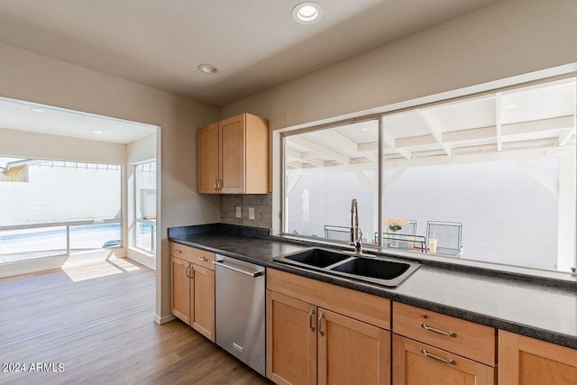 kitchen featuring dishwasher, beamed ceiling, tasteful backsplash, sink, and hardwood / wood-style floors