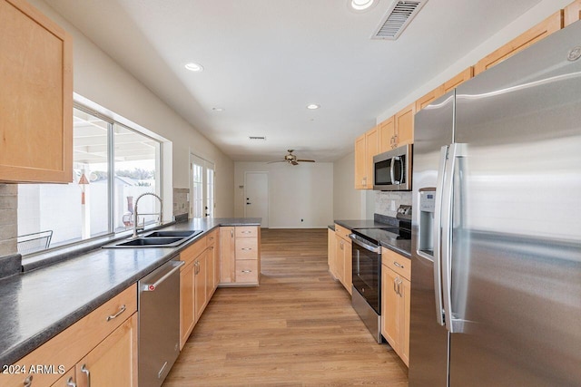 kitchen featuring sink, kitchen peninsula, tasteful backsplash, stainless steel appliances, and light wood-type flooring