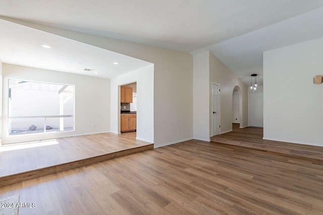 unfurnished living room featuring lofted ceiling and hardwood / wood-style flooring