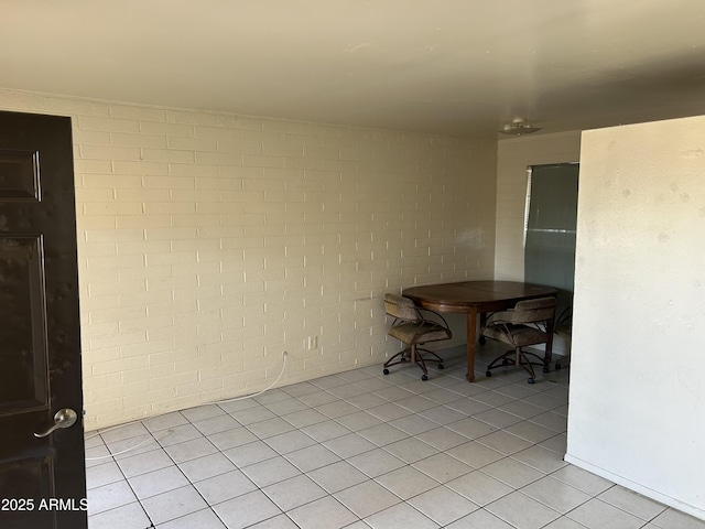 dining room with light tile patterned flooring and brick wall