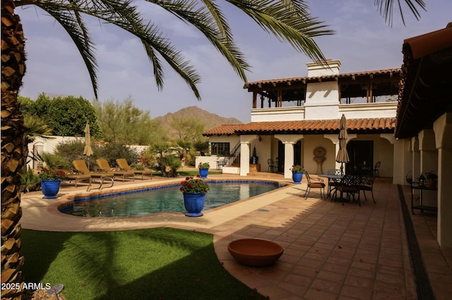 back of house featuring stucco siding, a mountain view, an outdoor pool, and a patio