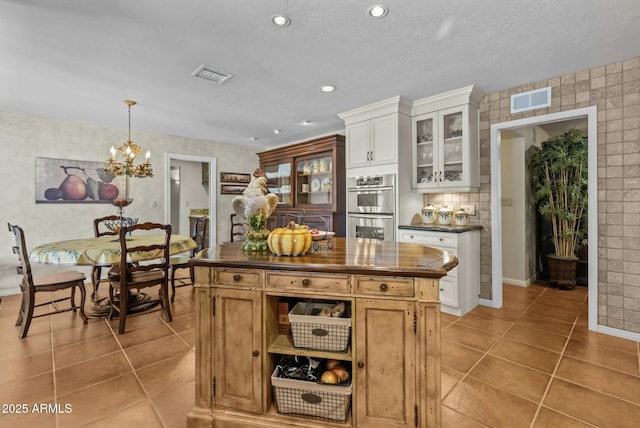 4726 E Sierra Vista Dr, Paradise Valley, AZ 85253 - kitchen featuring stainless steel double oven, visible vents, an inviting chandelier, and light tile patterned flooring