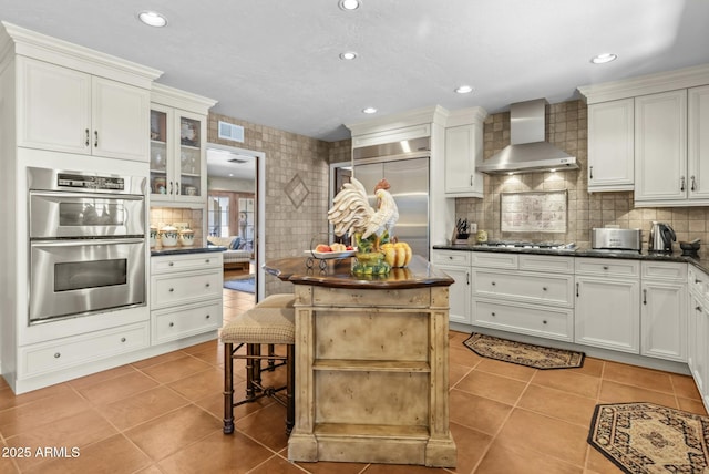 4726 E Sierra Vista Dr, Paradise Valley, AZ 85253 - kitchen featuring light tile patterned floors, wall chimney exhaust hood, tasteful backsplash, visible vents, and appliances with stainless steel finishes
