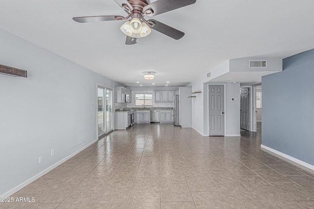 9609 N 44th Ave, Glendale, AZ 85302 - unfurnished living room featuring visible vents, baseboards, ceiling fan, and a healthy amount of sunlight
