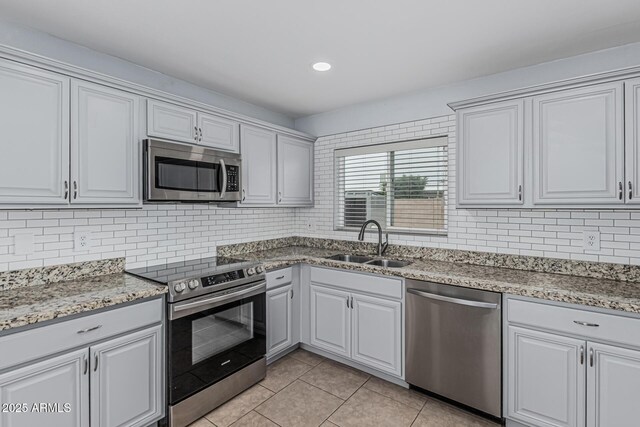 9609 N 44th Ave, Glendale, AZ 85302 - kitchen with appliances with stainless steel finishes, tasteful backsplash, light stone countertops, a sink, and light tile patterned flooring