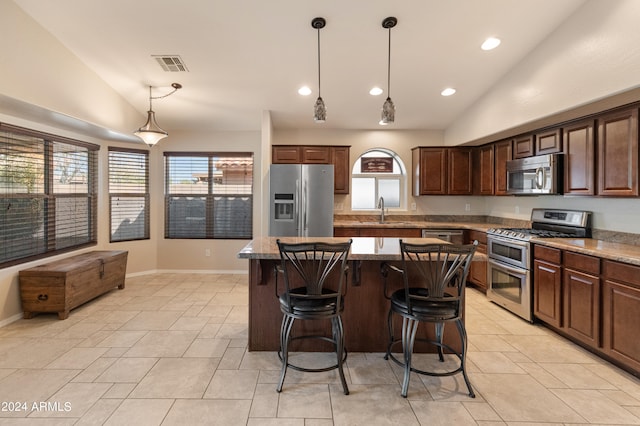 kitchen featuring lofted ceiling, appliances with stainless steel finishes, a center island, and light tile floors