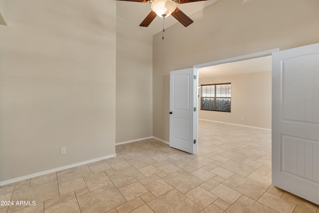 tiled spare room featuring ceiling fan and a high ceiling