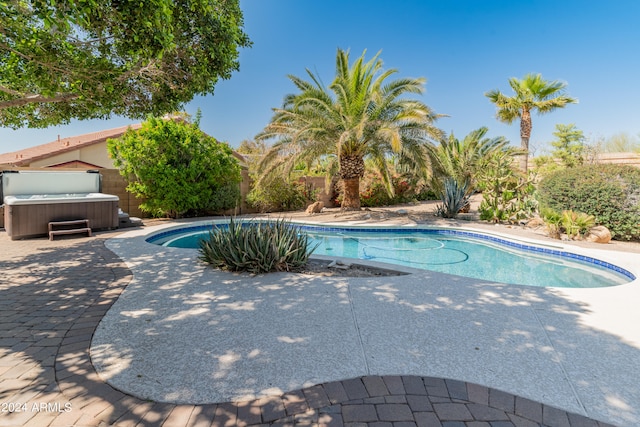 view of swimming pool featuring a patio and a hot tub