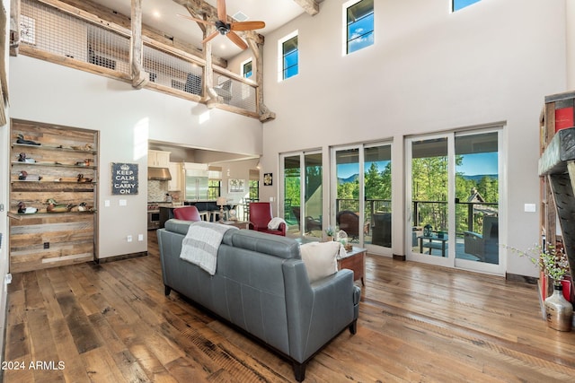 living room with ceiling fan, a high ceiling, and hardwood / wood-style floors
