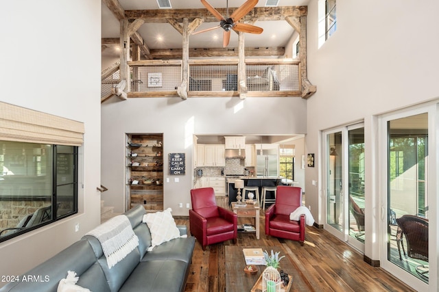 living room with a towering ceiling, a healthy amount of sunlight, and wood-type flooring