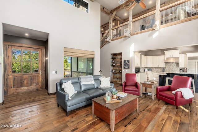 living room featuring ceiling fan, beamed ceiling, dark hardwood / wood-style flooring, and a high ceiling