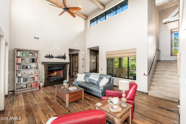 living room with ceiling fan, beamed ceiling, a high ceiling, and dark hardwood / wood-style floors