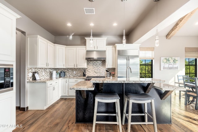 kitchen with built in appliances, white cabinetry, a center island with sink, and dark wood-type flooring
