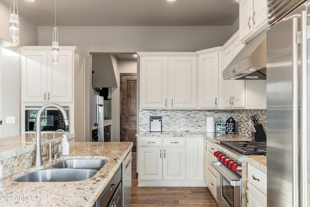 kitchen with premium appliances, wood-type flooring, sink, white cabinetry, and pendant lighting
