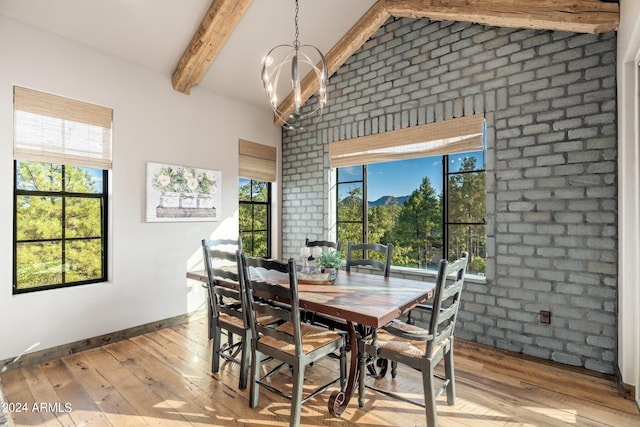 dining room featuring a wealth of natural light, vaulted ceiling with beams, and light hardwood / wood-style floors