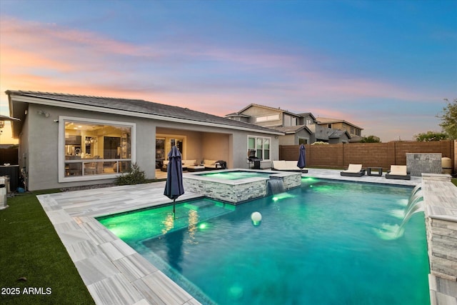 pool at dusk with a patio, pool water feature, and an in ground hot tub