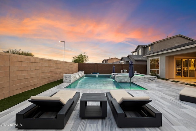 pool at dusk featuring an in ground hot tub and pool water feature