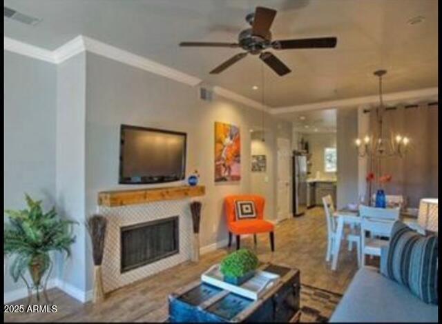9450 E Becker Ln Unit 2099, Scottsdale, AZ 85260 - living room featuring ceiling fan, a glass covered fireplace, a chandelier, crown molding, and baseboards